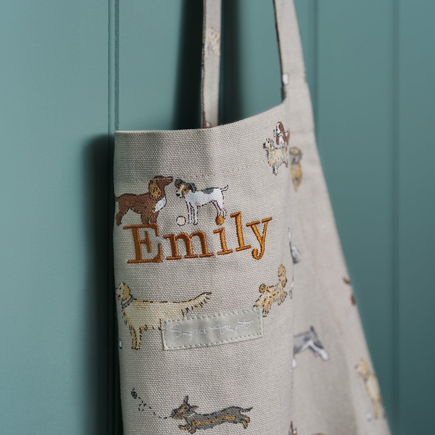 Close up shot of Sophie Allport's Adult Apron that has been personalised with the words Emily, on her new Doggy Daycare Design 