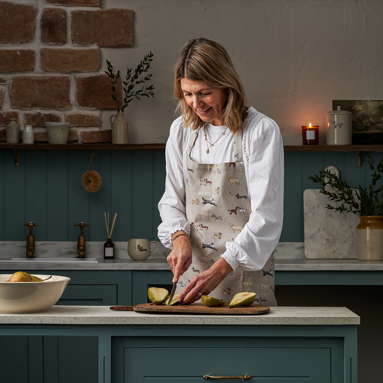 Sophie Allport chopping pears in her kitchen wearing her Doggy Daycare Adult Apron